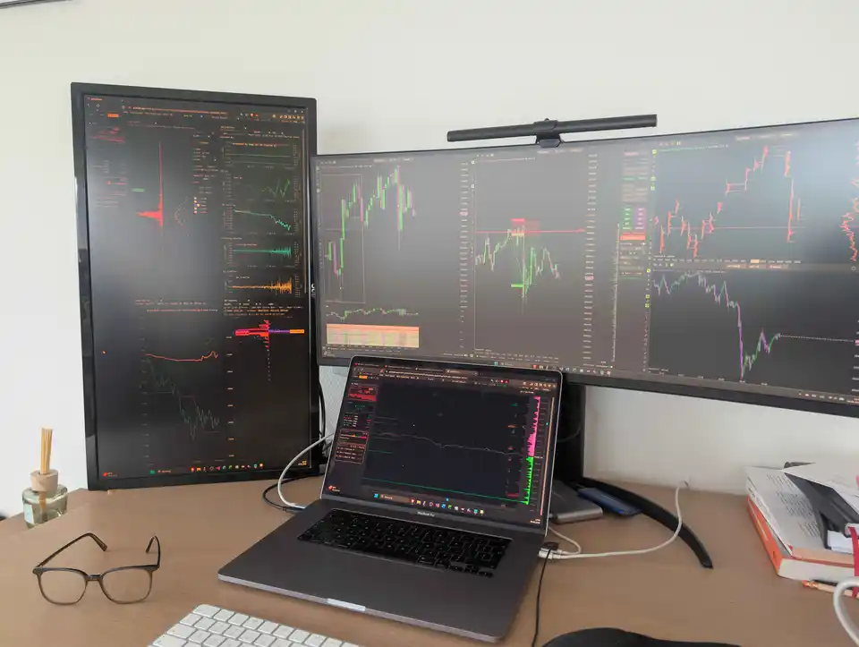 Laptop and multi-monitor trader desk running gwtrade.app charts and order-flow analytics